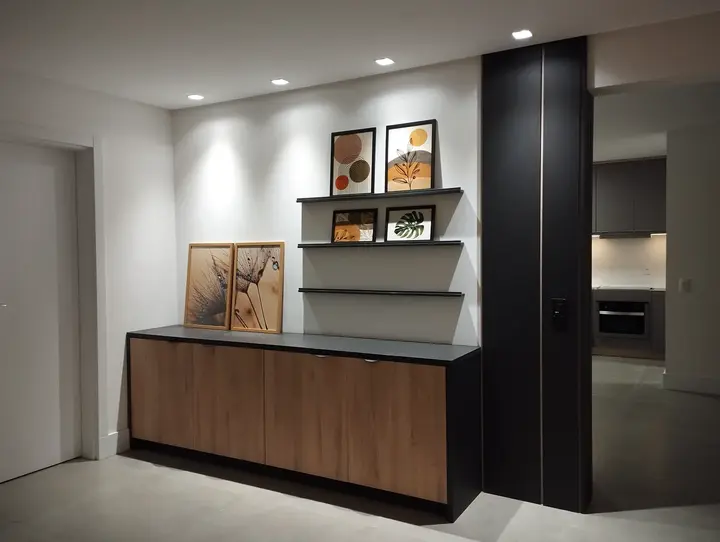 Hall com buffet amadeirado, estrutura preta e prateleiras para quadros